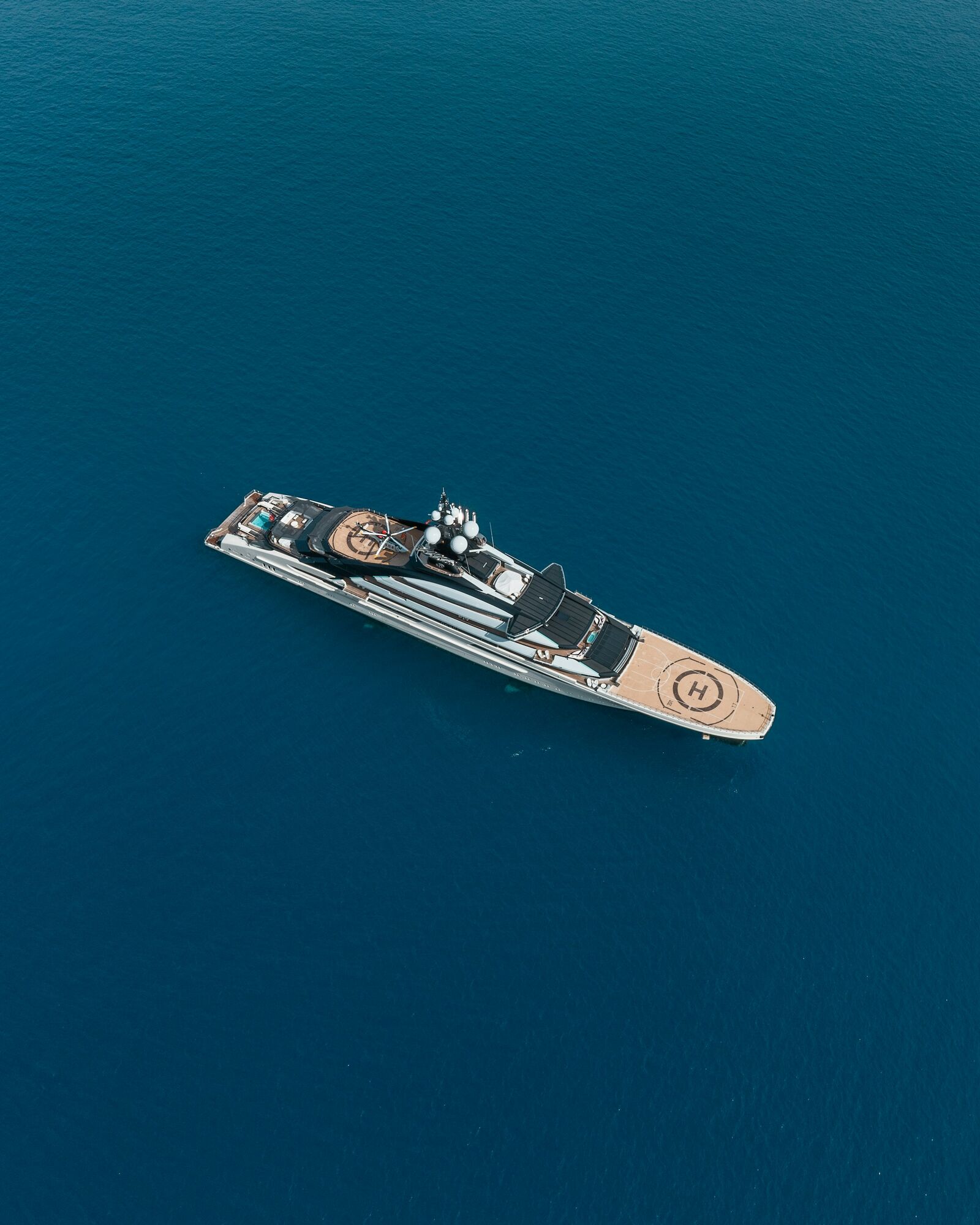 Aerial view of a superyacht at anchor in deep blue water